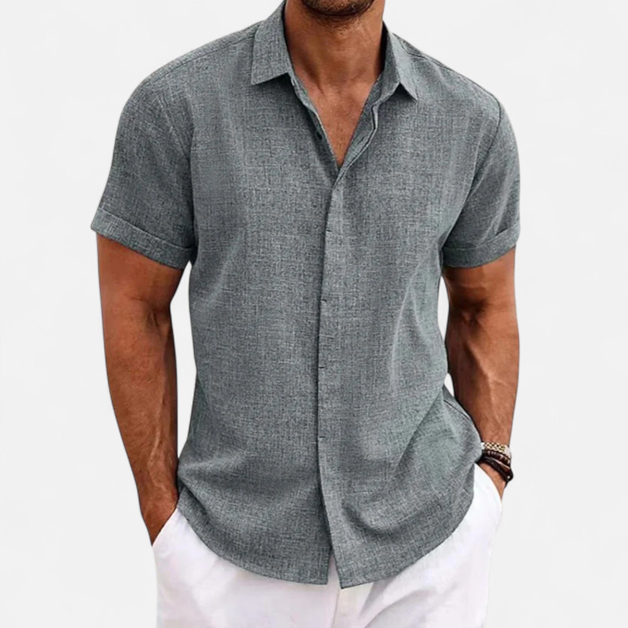 Man wearing a gray short-sleeve button-up shirt and white pants on a light gray background