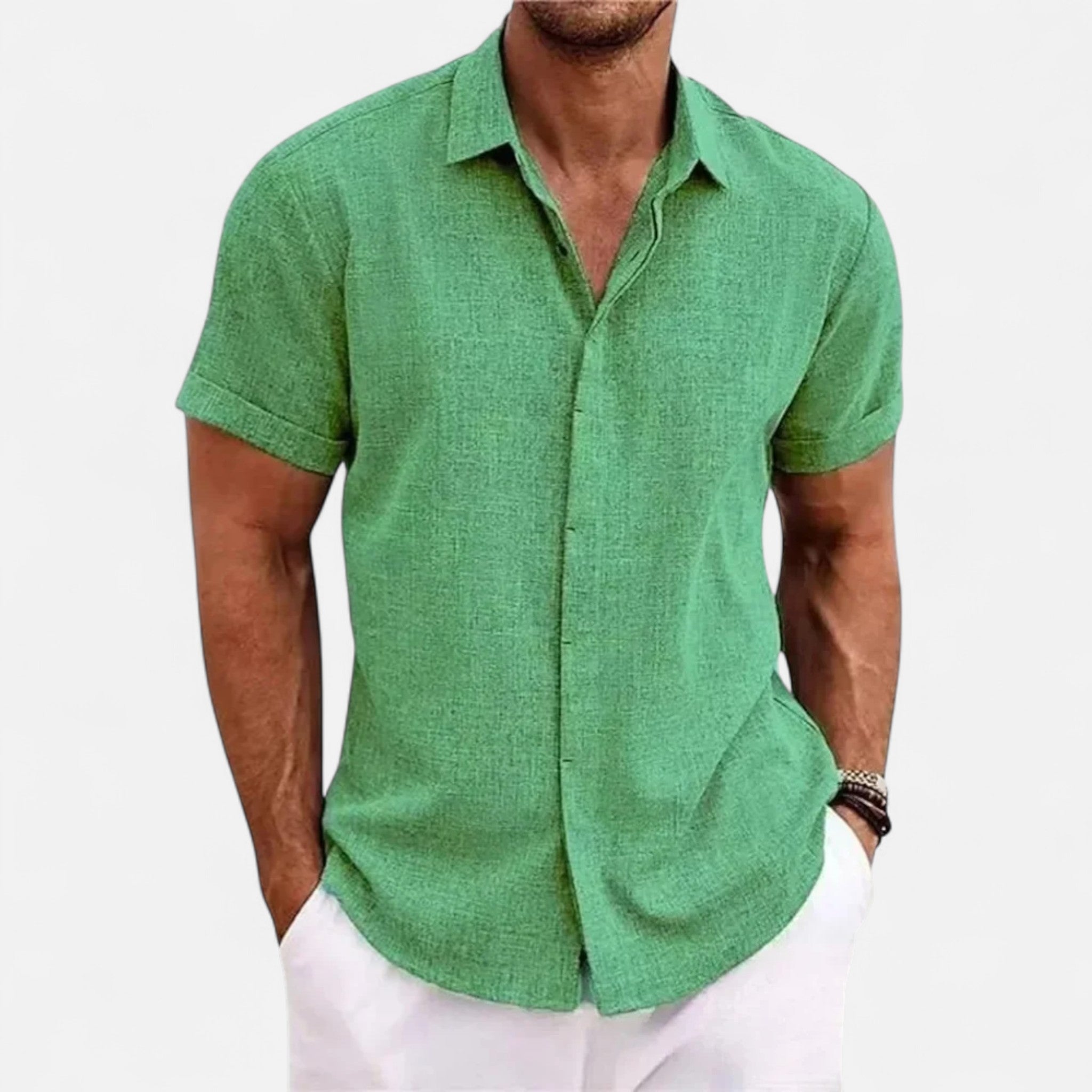 Man wearing a green short-sleeve shirt and white pants on a light gray background
