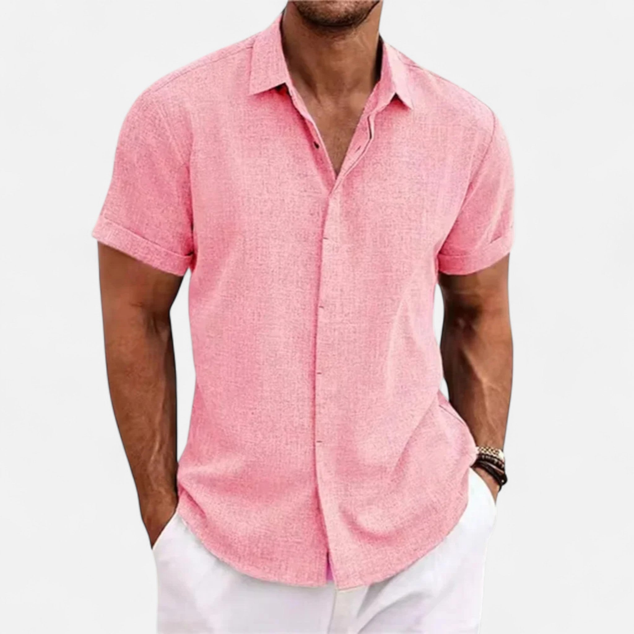 Man wearing a pink short-sleeve shirt and white pants on a light gray background