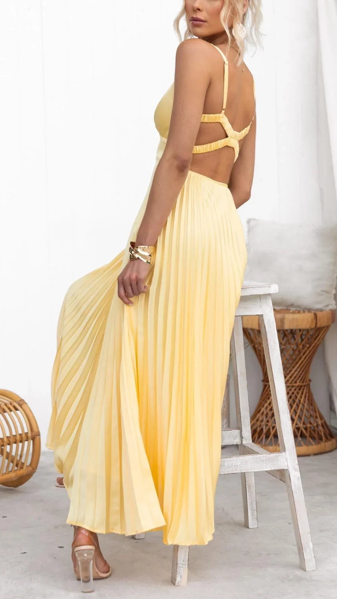 Woman wearing a yellow dress sitting on a chair with a white curtain in the background