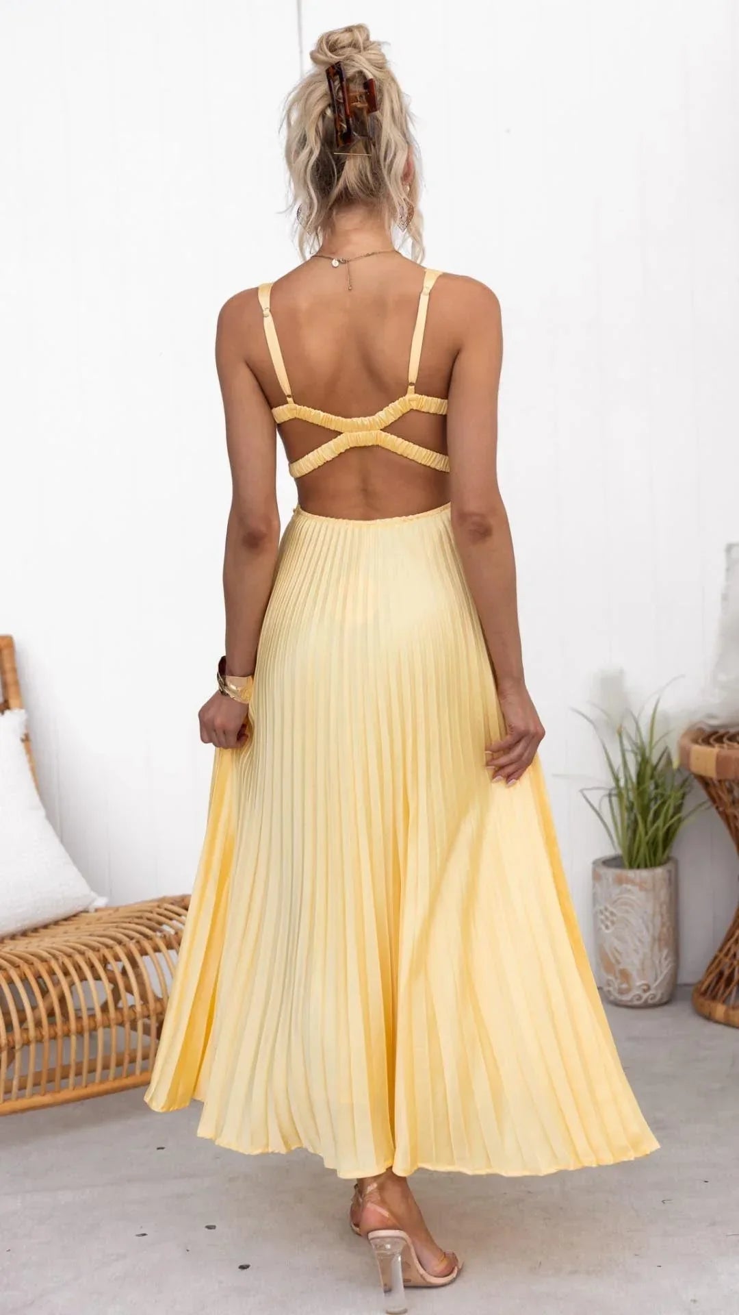 Woman wearing a yellow dress with thin straps in a minimal indoor setting