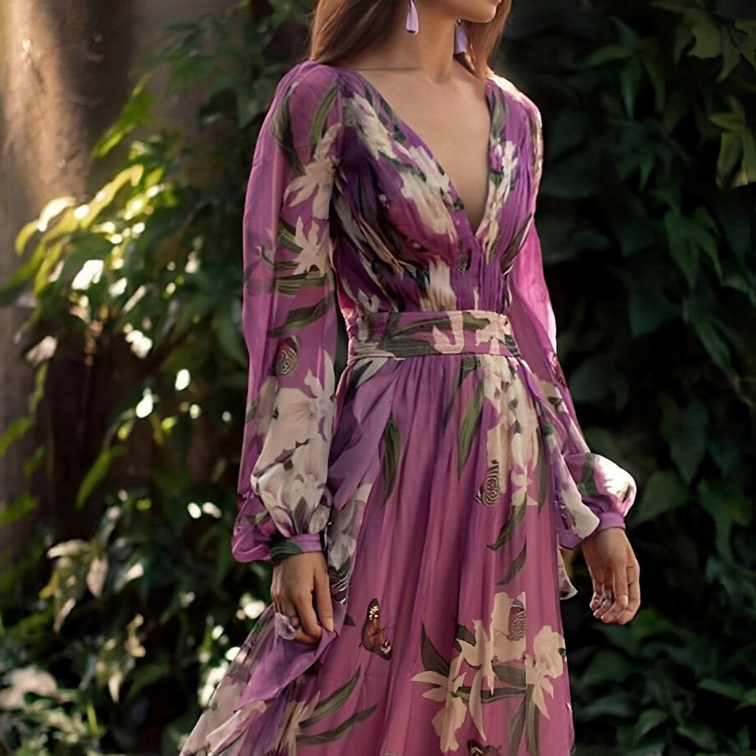 Woman wearing a purple floral dress standing in front of green foliage
