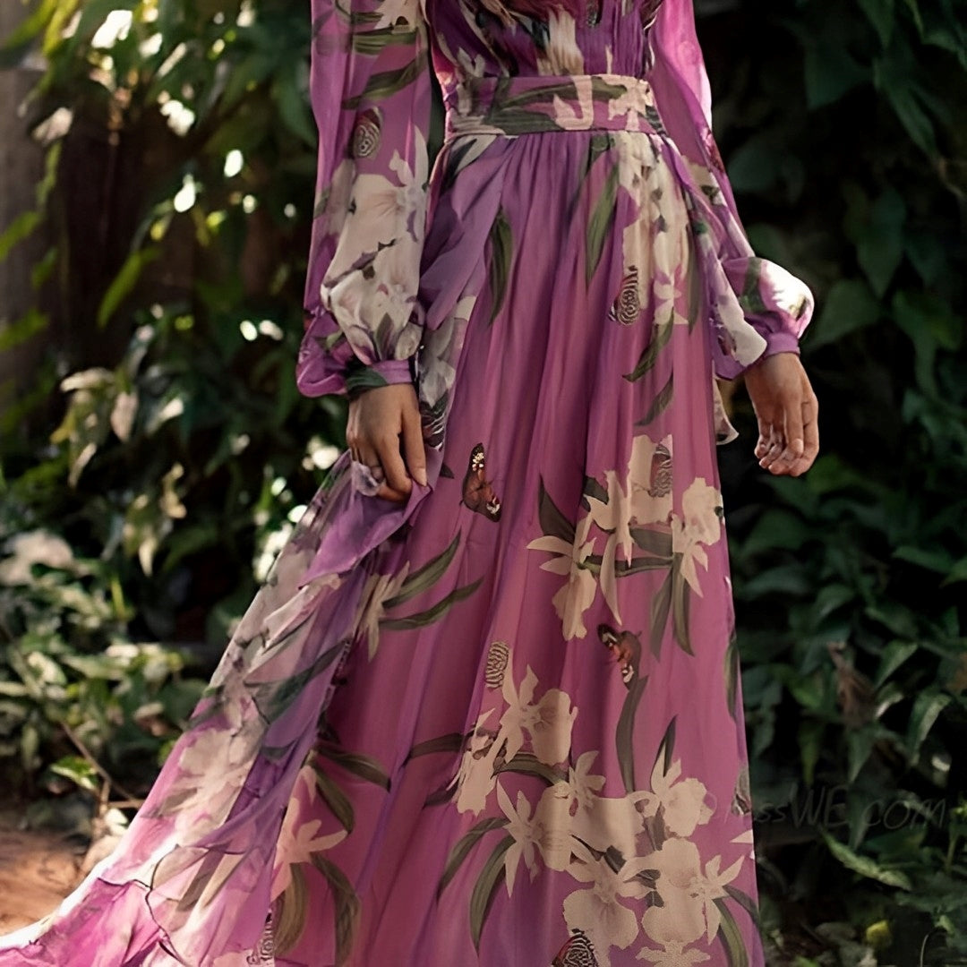 Person wearing a long, floral-patterned dress with a blurred green background