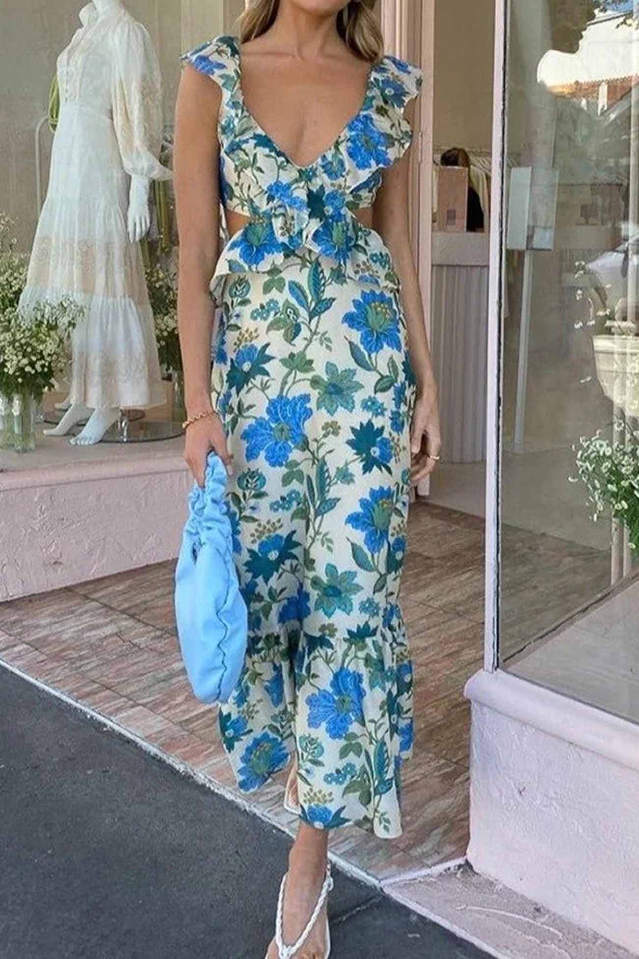 Woman in a floral dress holding a blue clutch outside a store.