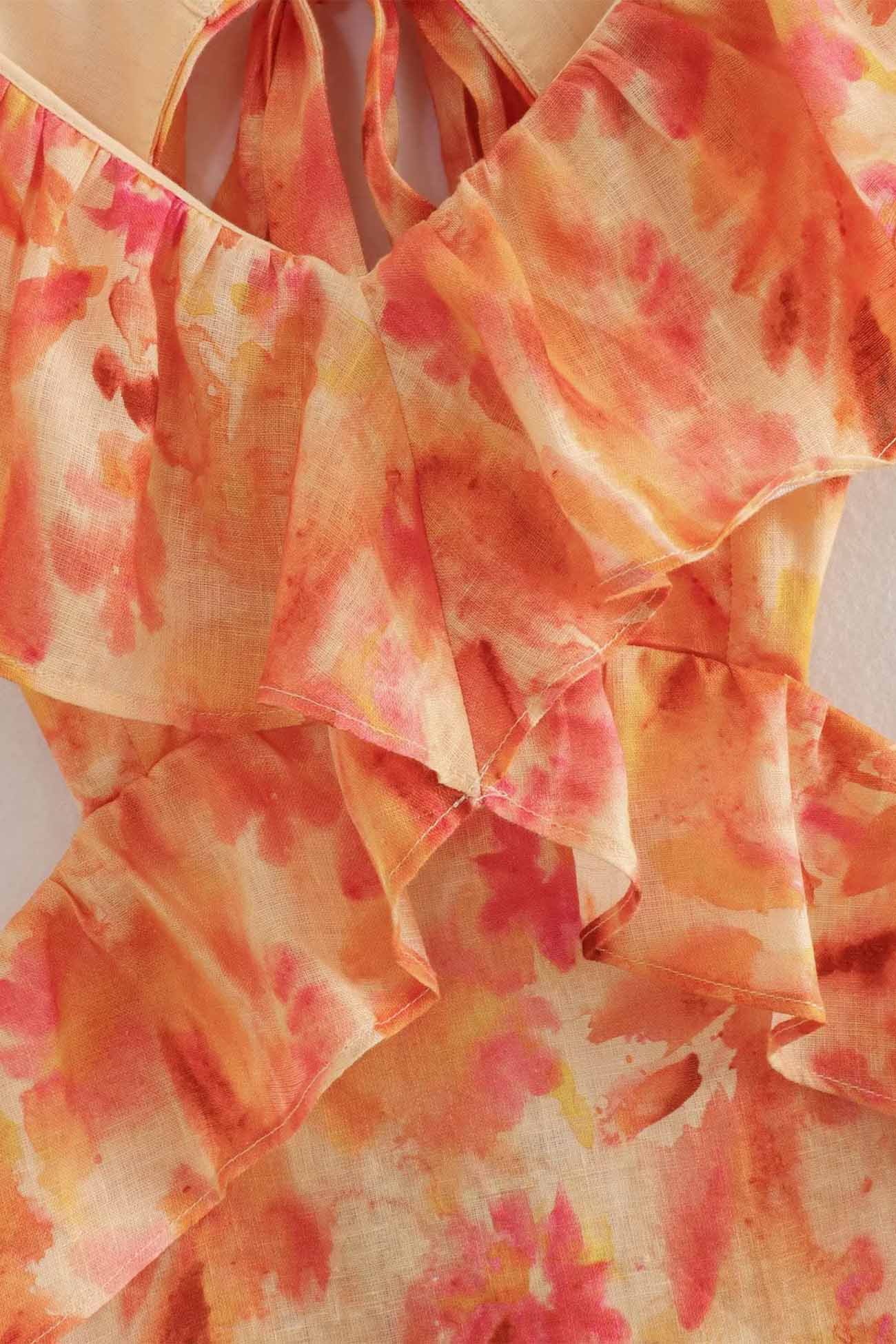 Close-up of a ruffled fabric with orange and pink watercolor pattern