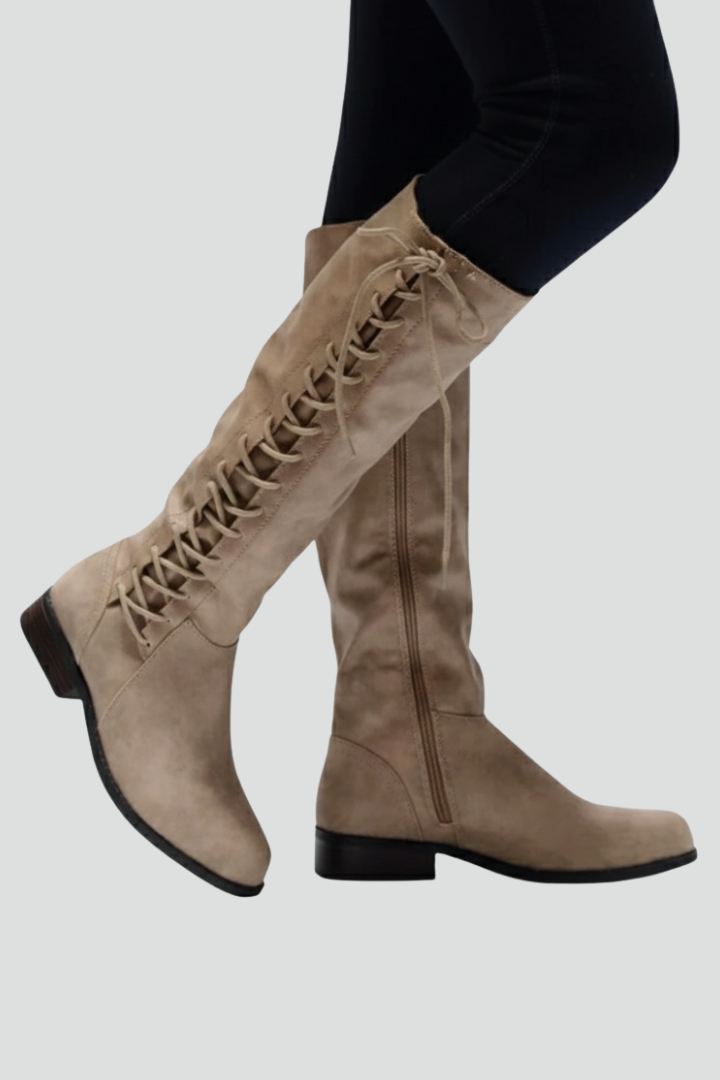 Beige knee-high boots with lace-up design on a light gray background