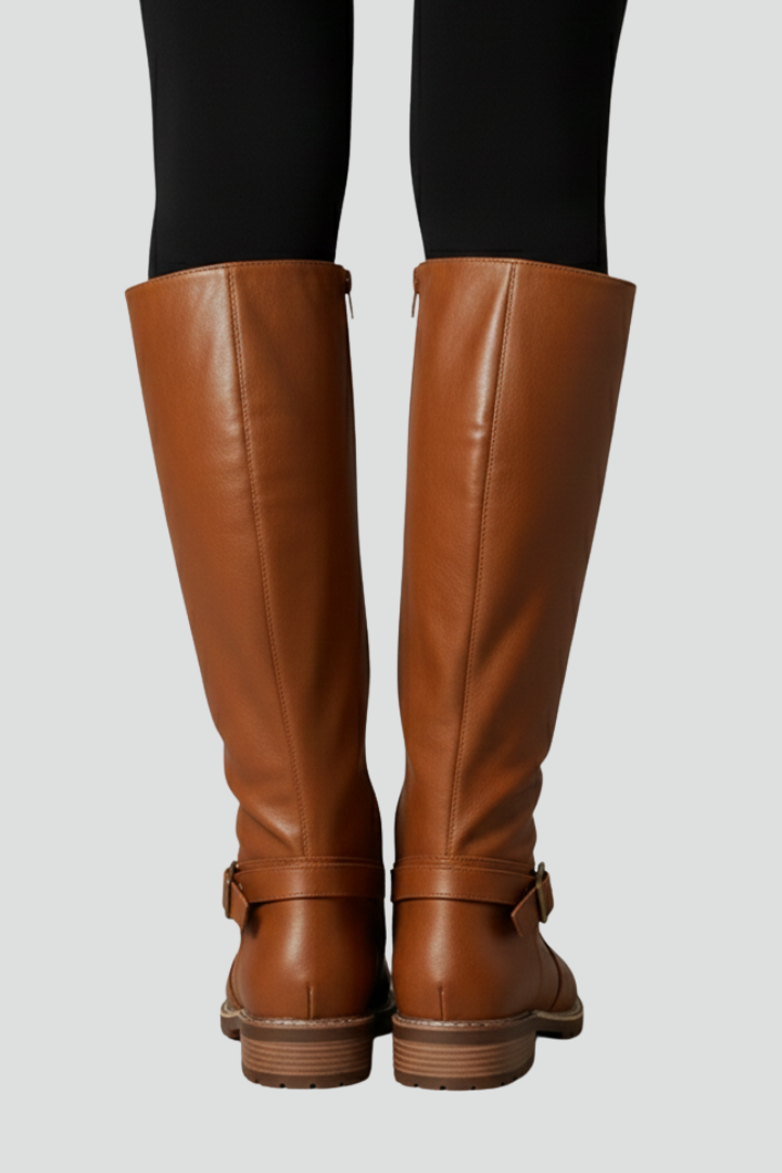 Brown knee-high boots worn with black leggings on a light gray background