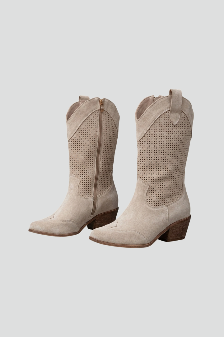 Pair of beige cowboy boots on a light gray background