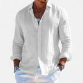 Man wearing a white button-up shirt with rolled-up sleeves on a light gray background