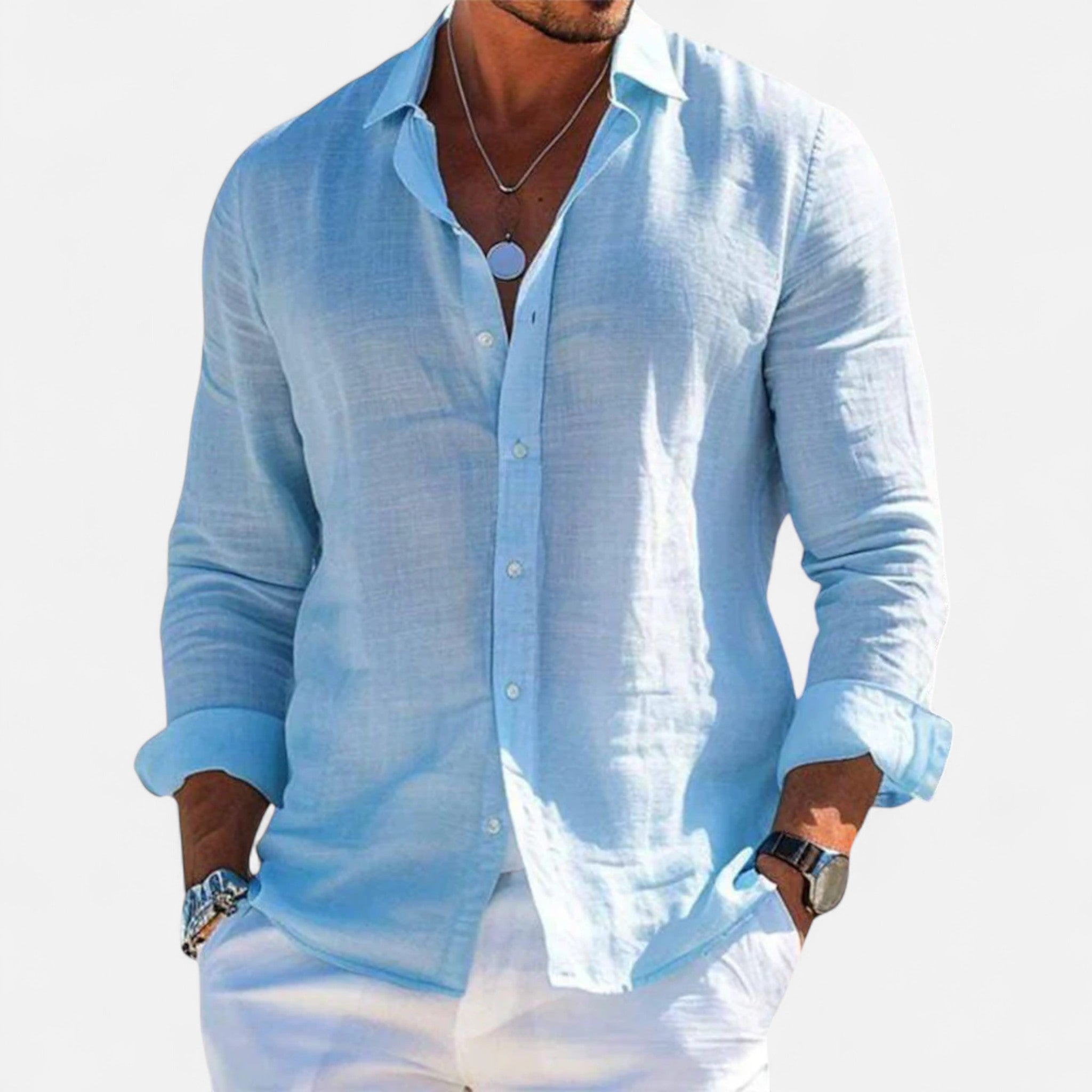 Man wearing a light blue linen shirt with rolled-up sleeves against a white background