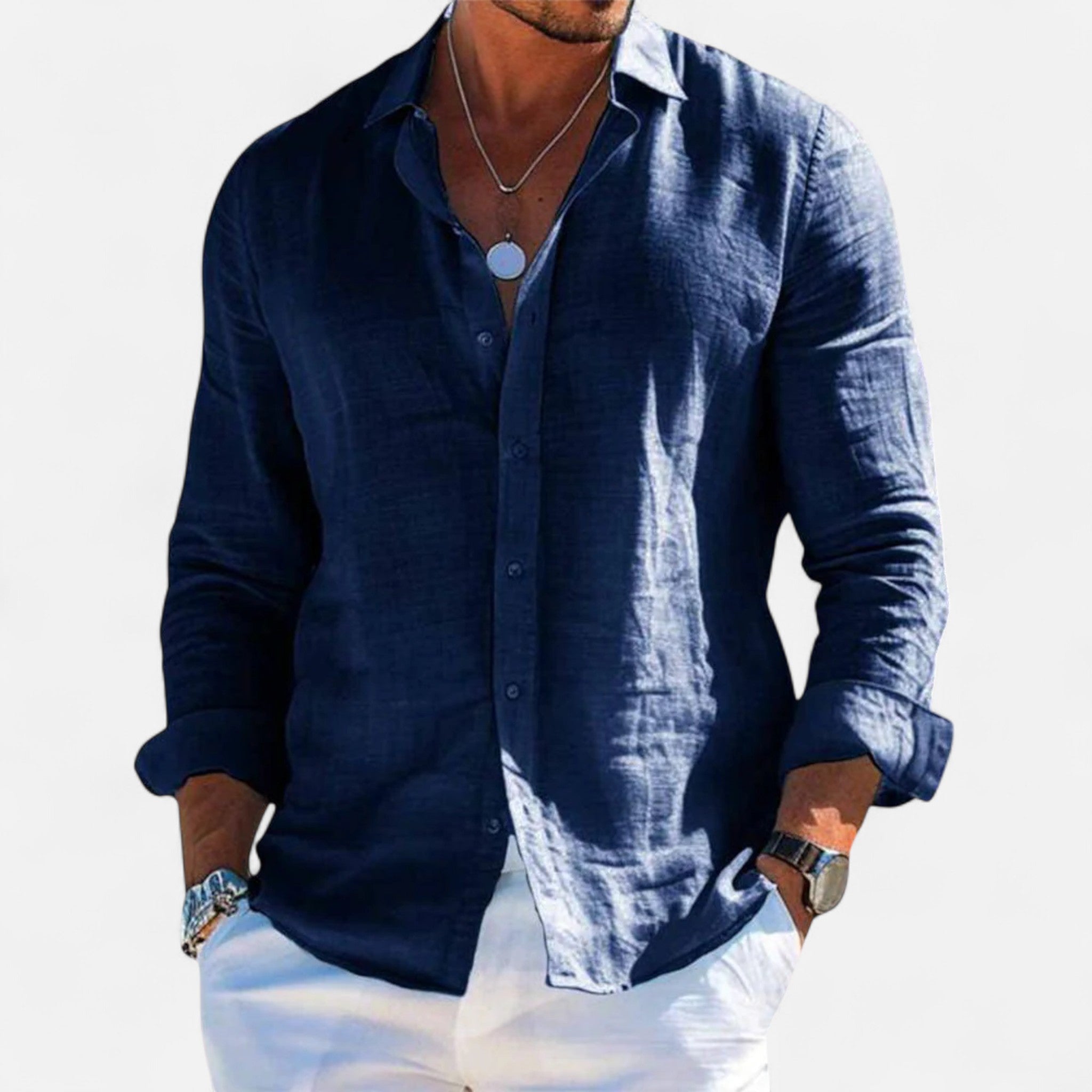 Man wearing a navy blue button-up shirt with white pants on a light gray background