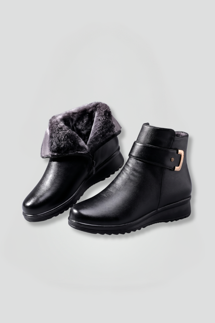 Black ankle boots with fur lining on a light gray background