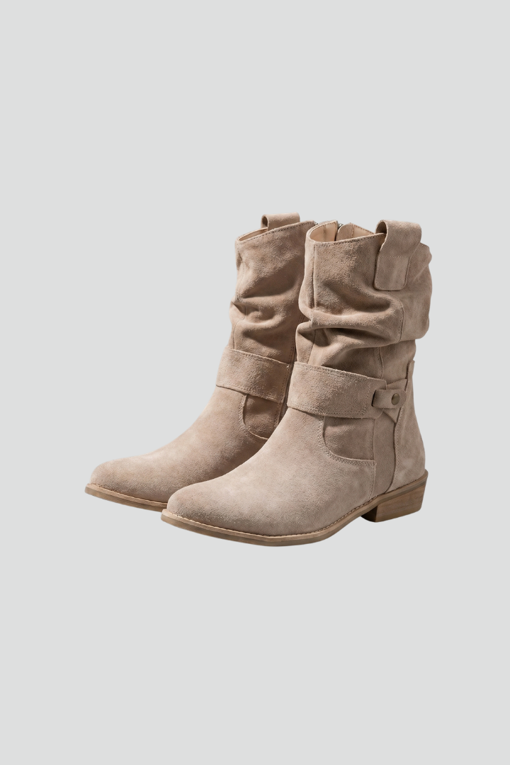 Pair of beige suede boots on a light gray background