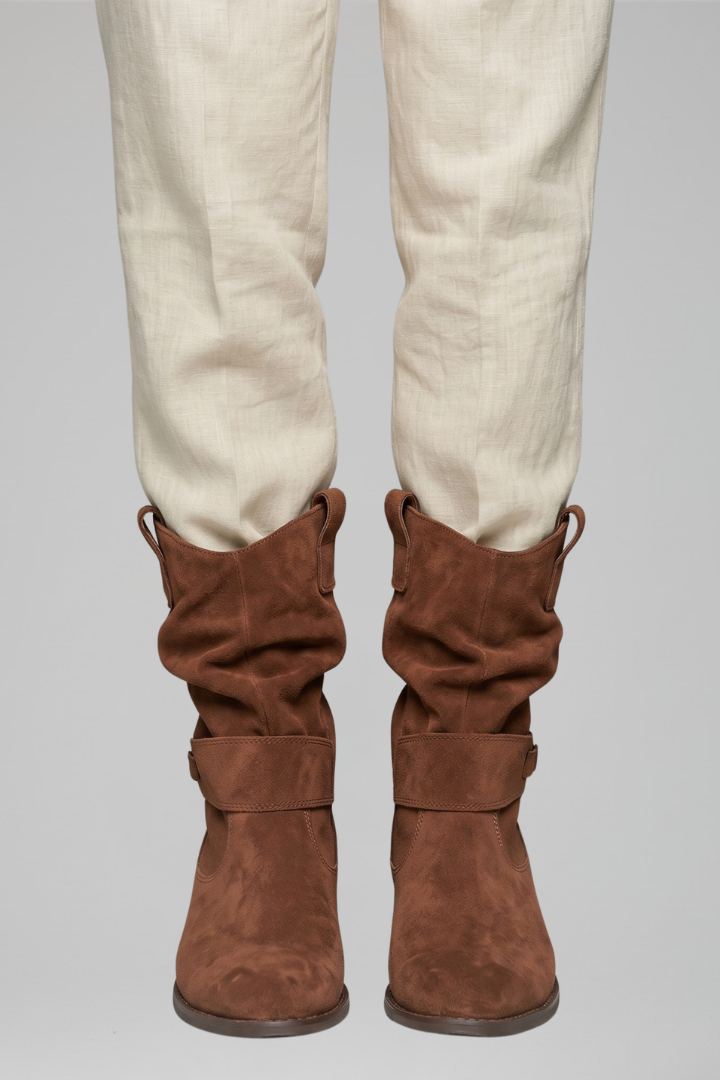 Brown knee-high boots worn with beige pants on a gray background