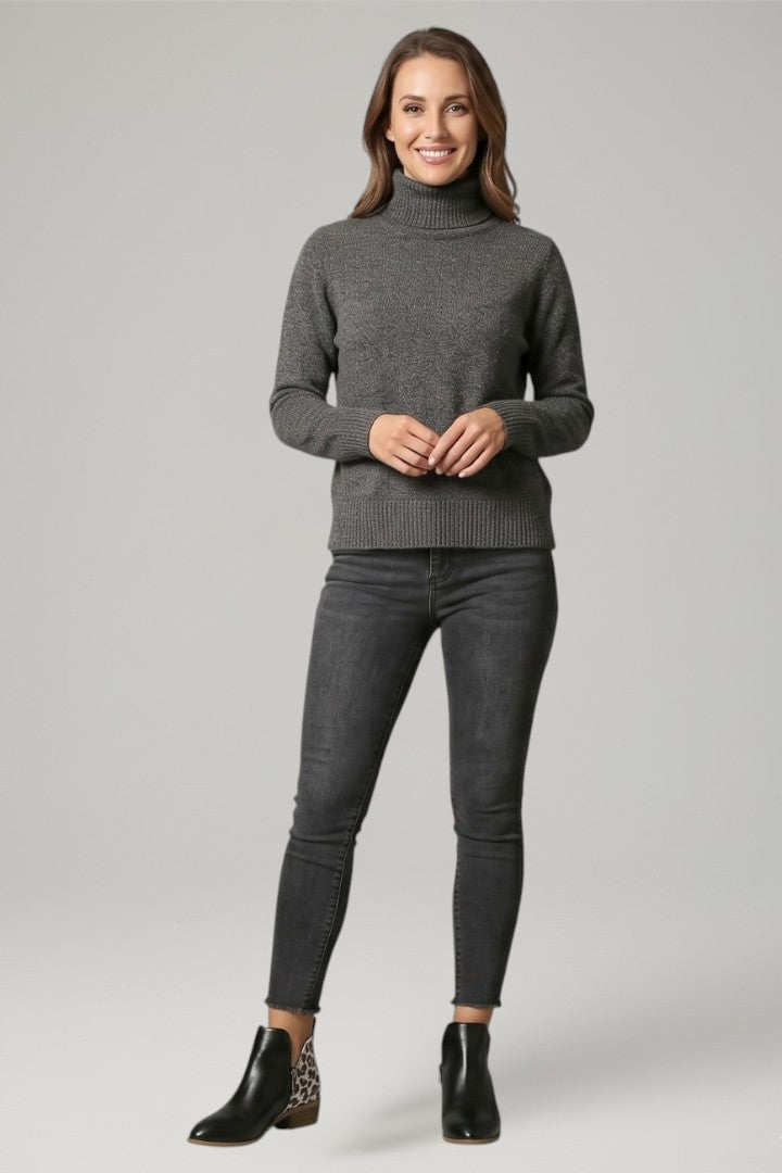 Woman wearing a gray turtleneck sweater and jeans on a light gray background