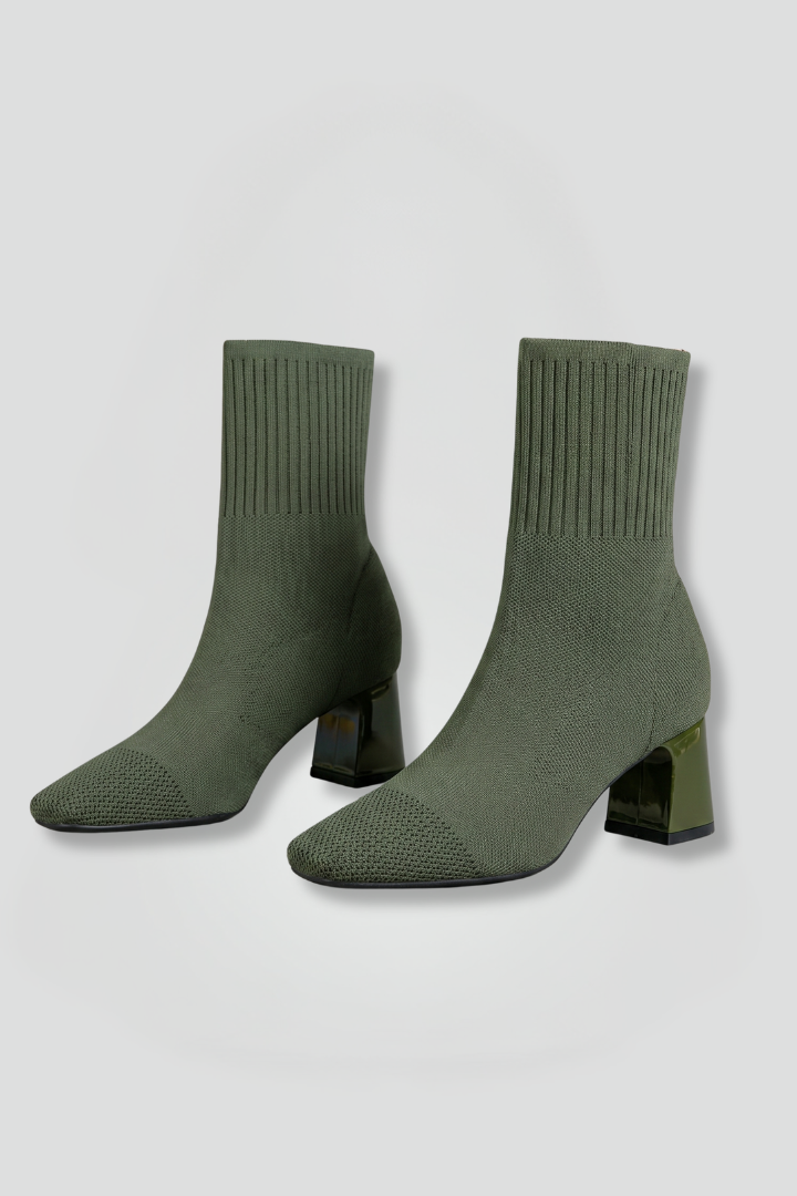 Green sock boots with block heels on a light gray background