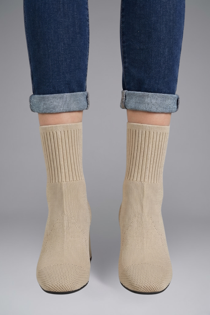 Beige socks worn with rolled-up jeans on a gray background
