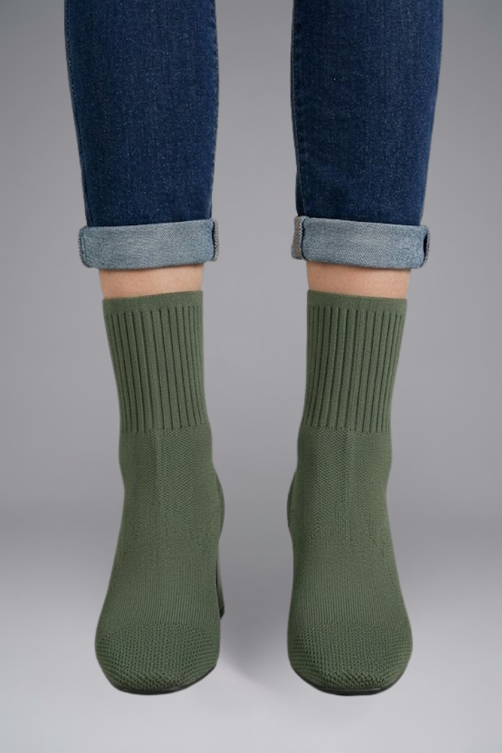 Green socks worn with rolled-up jeans on a gray background