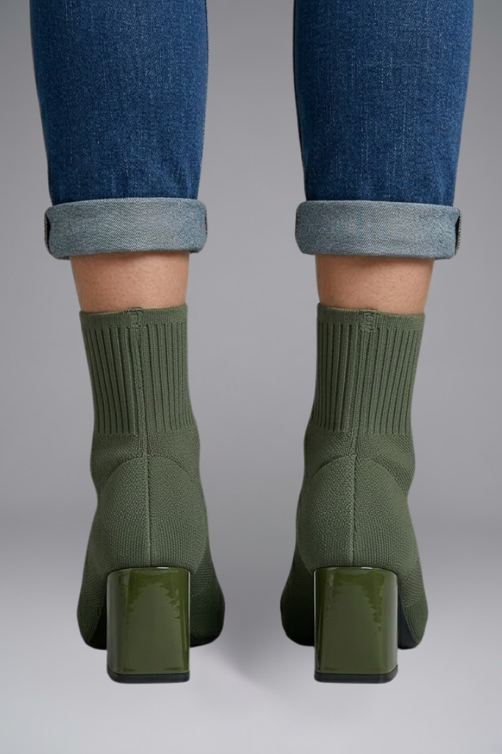 Green sock boots worn with rolled-up jeans on a gray background