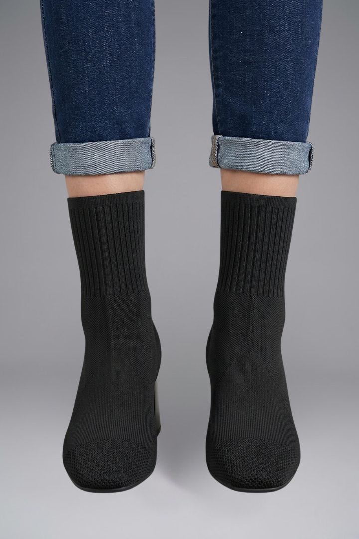 Black socks worn with rolled-up jeans on a gray background