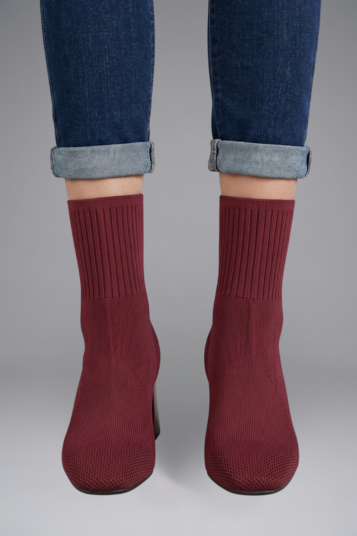 Maroon socks worn with rolled-up jeans on a gray background