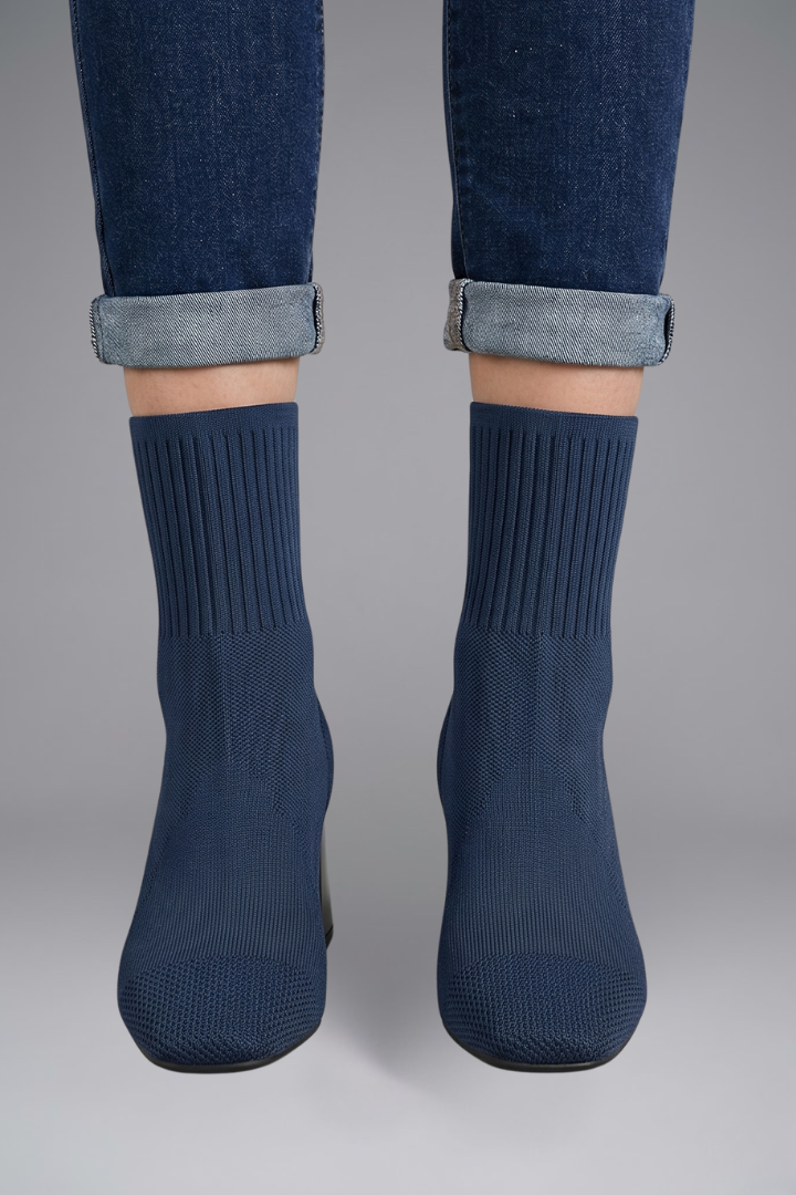 Navy blue socks worn with rolled-up jeans on a gray background