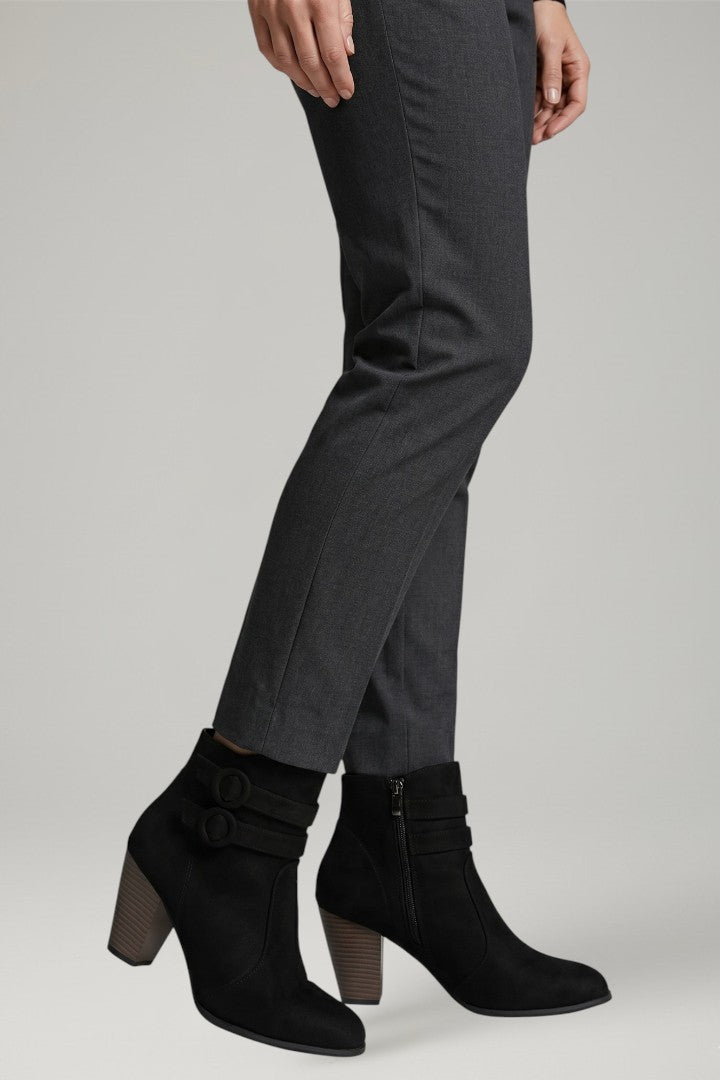Person wearing gray pants and black ankle boots on a light gray background