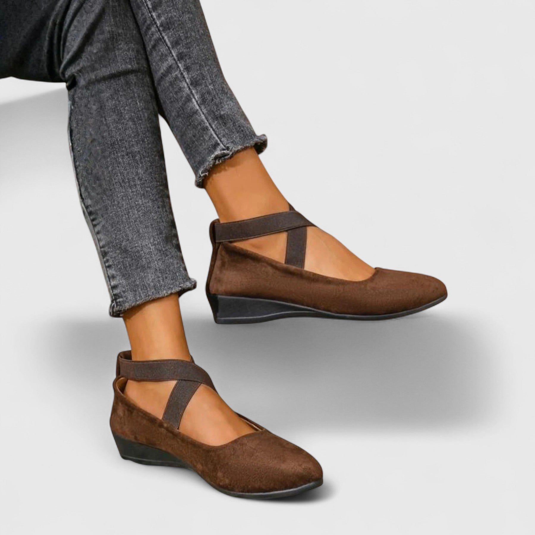 Brown shoes with strap worn with gray jeans on a light gray background