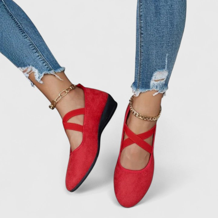 Red flat shoes worn with ripped jeans on a white background