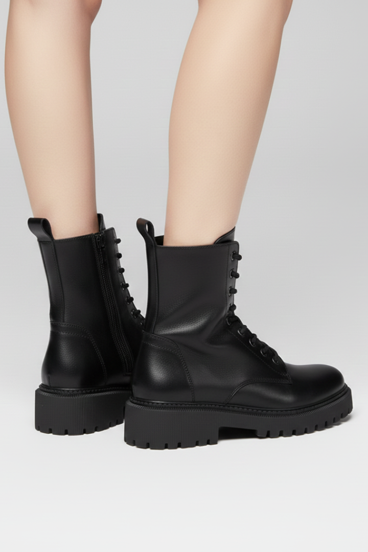 Black leather boots worn by a person on a light gray background