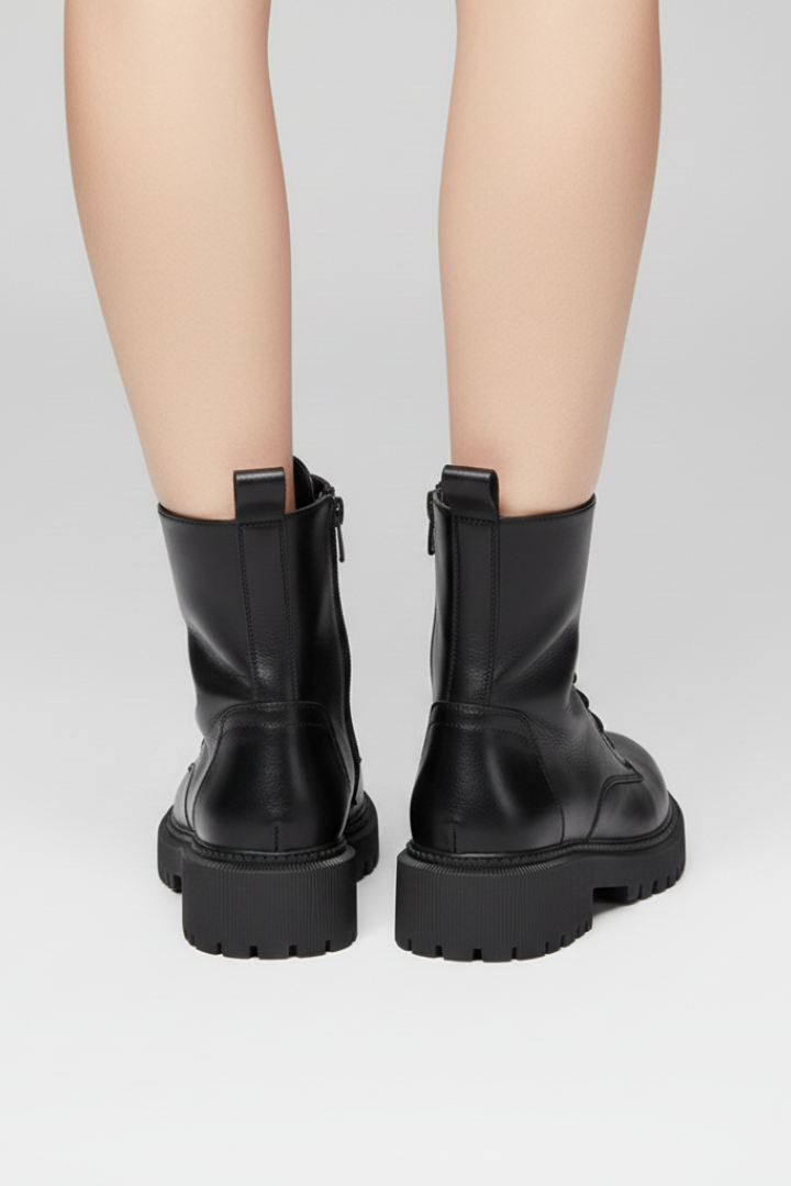 Black leather boots worn by a person on a light gray background