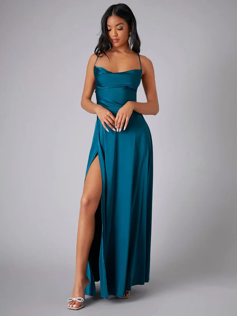 Woman wearing a teal evening gown with a high slit on a gray background