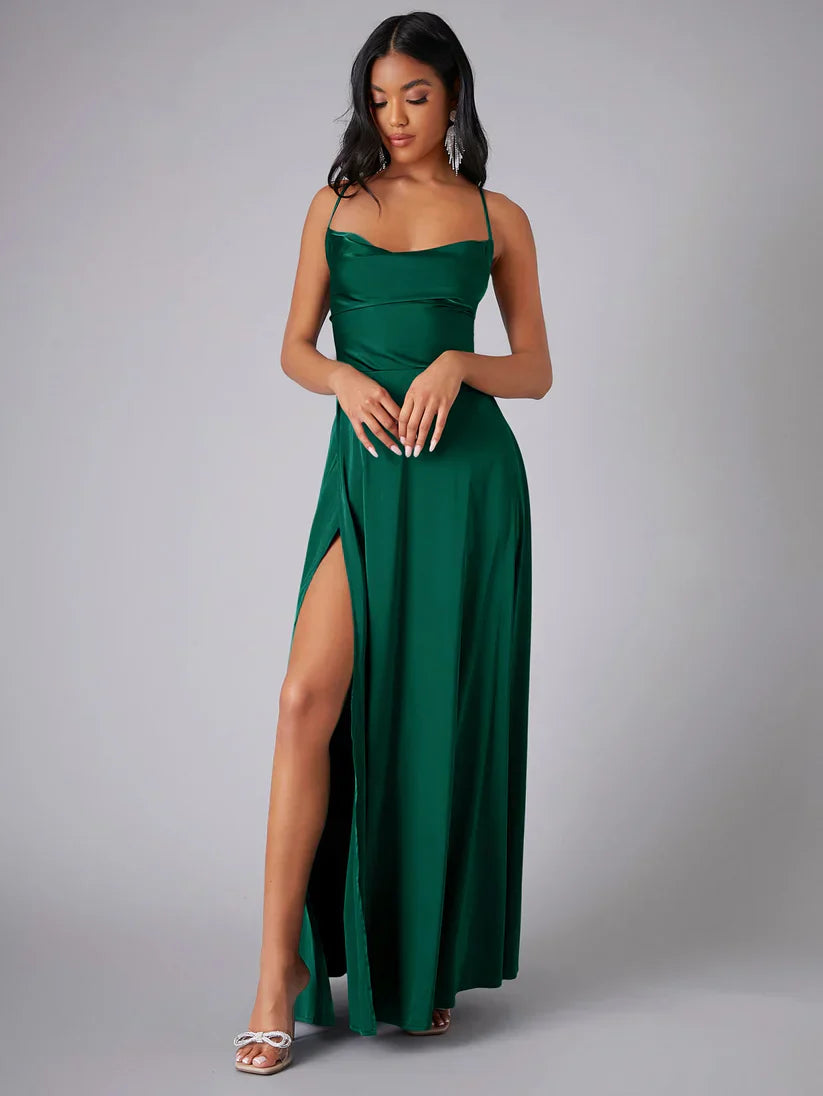Woman wearing a green evening gown with a slit on a gray background