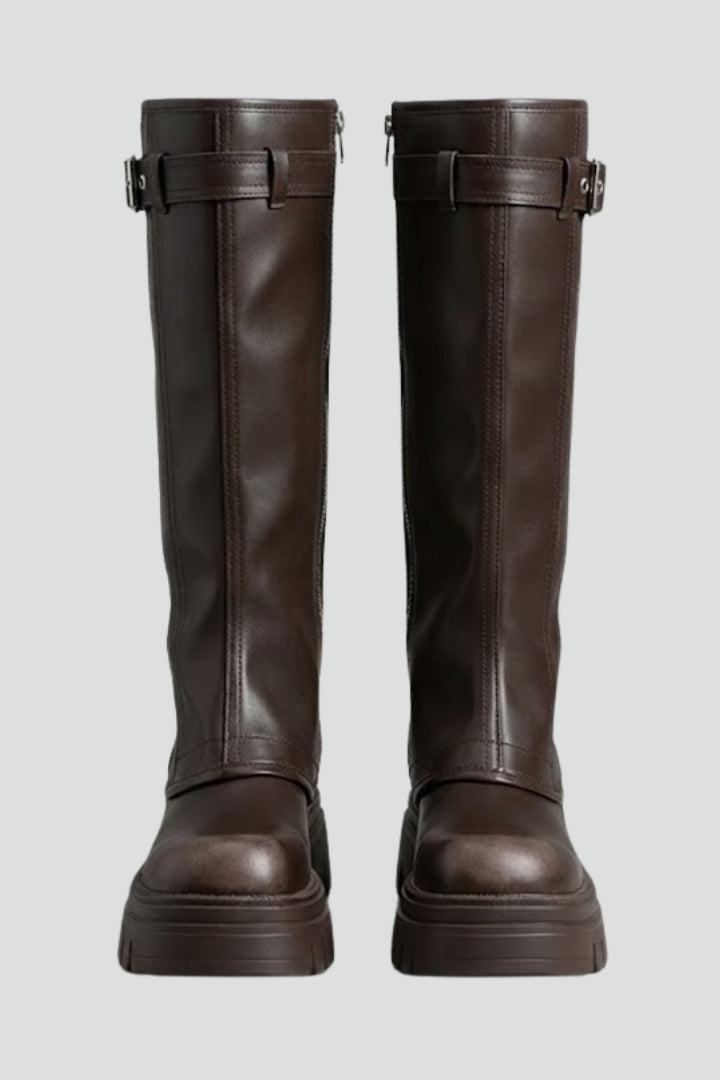 Pair of brown knee-high boots with buckles on a light gray background