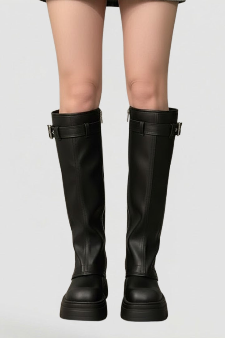 Black knee-high boots worn by a person on a light gray background