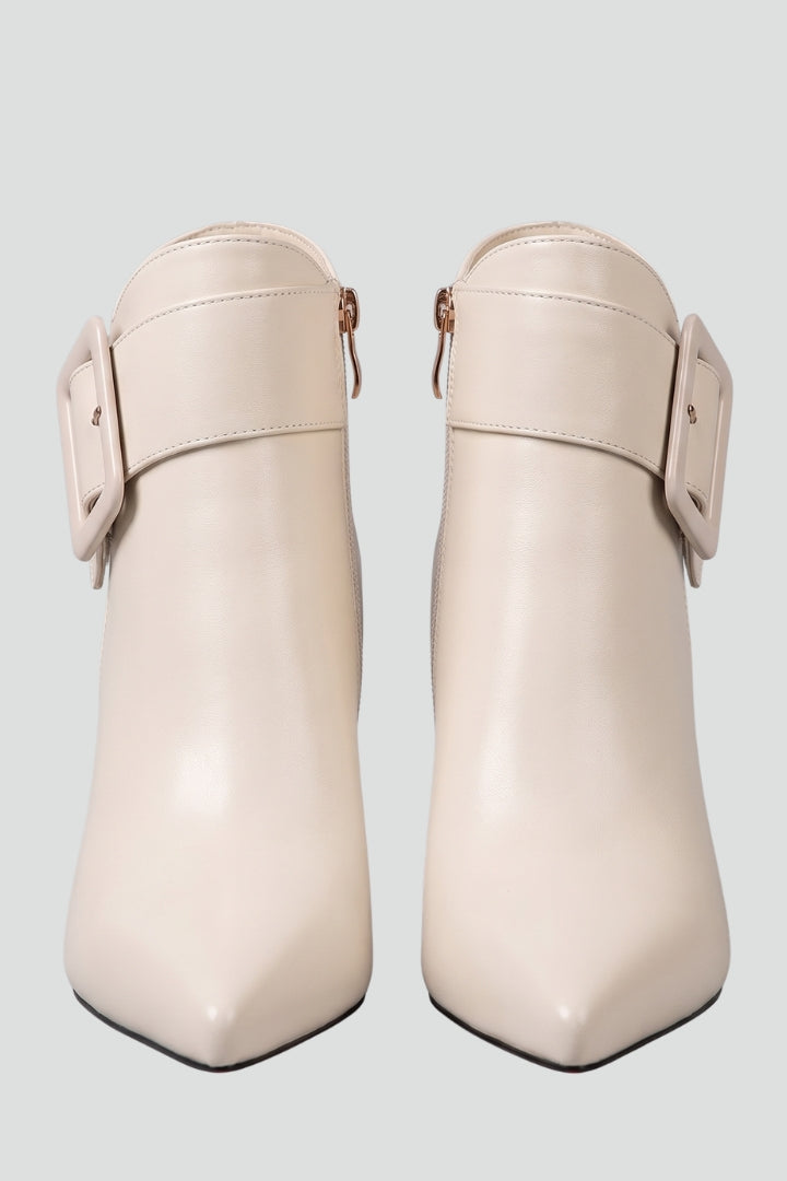 Pair of beige ankle boots with buckle details on a light gray background