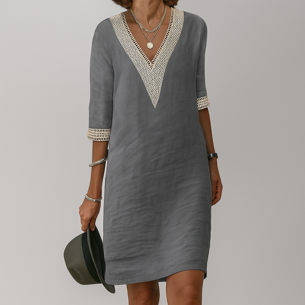 Woman wearing a gray dress with lace details on a plain background