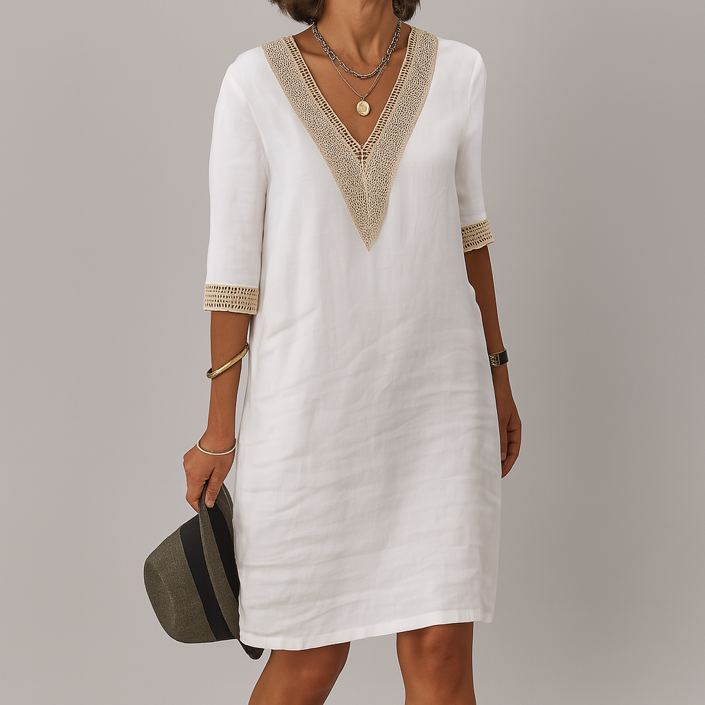 Woman wearing a white dress with gold accents against a gray background