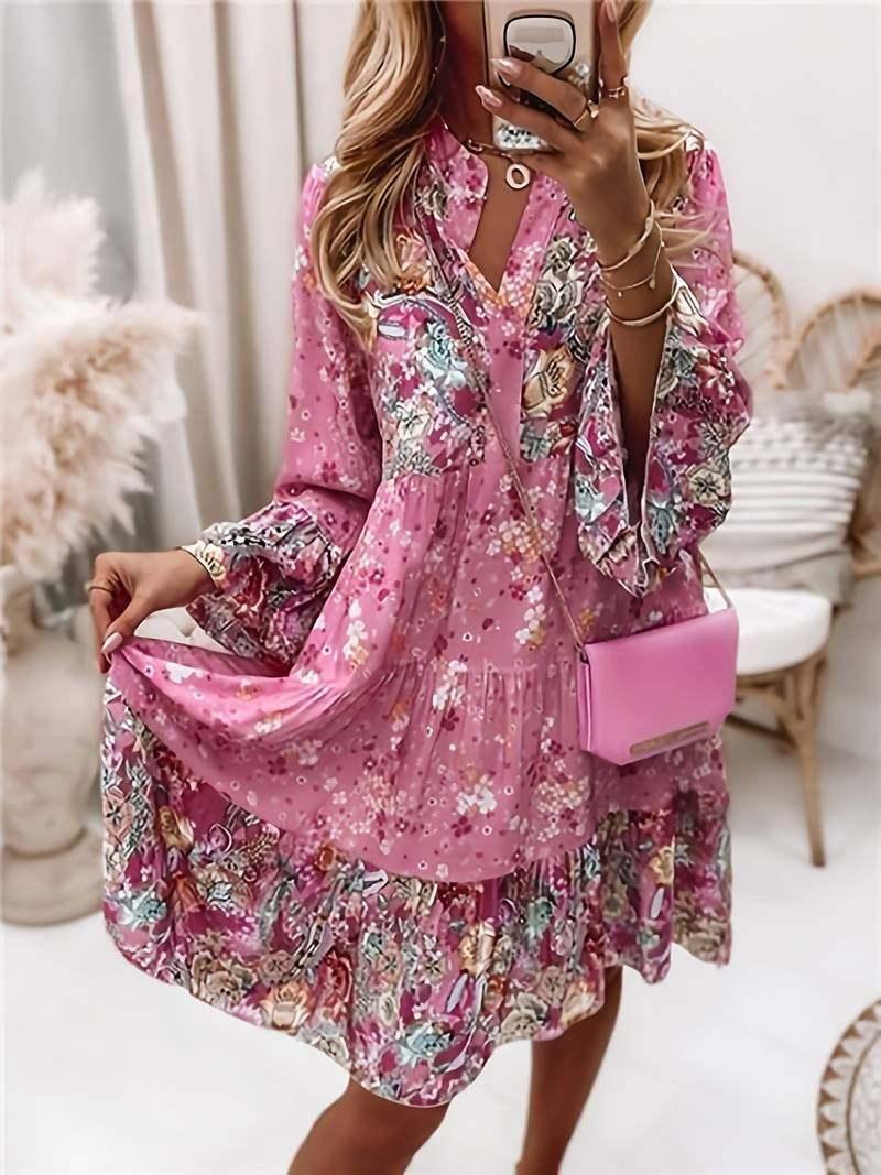 Woman wearing a pink floral dress holding a matching handbag indoors.