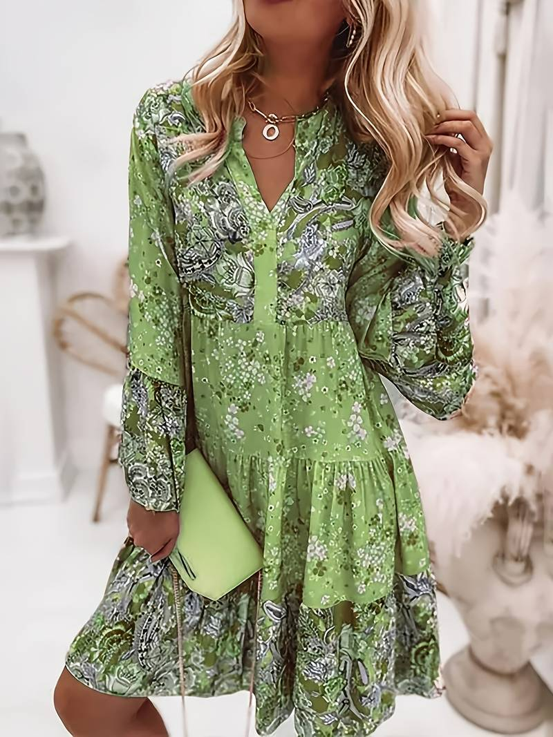 Woman wearing a green floral dress holding a green clutch in an indoor setting.