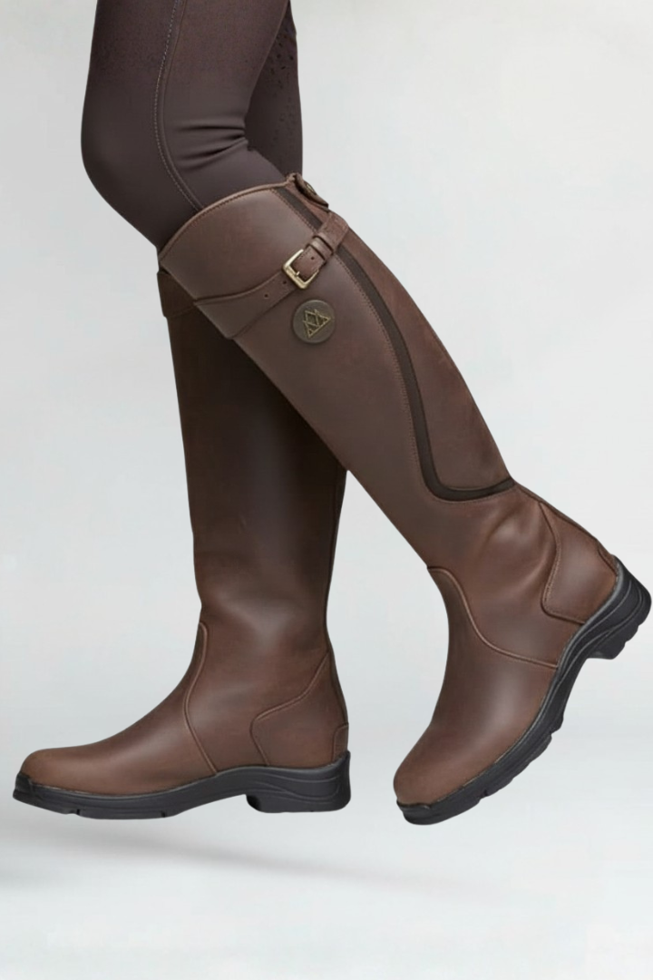 Brown riding boots with a buckle on a white background