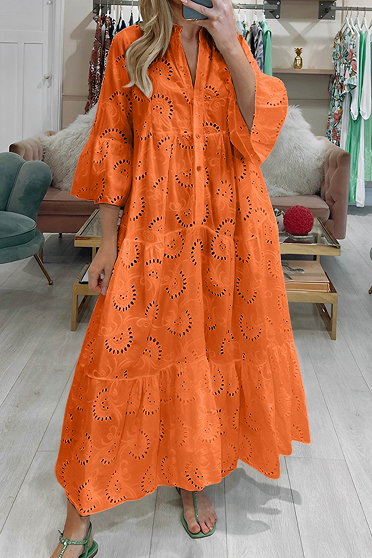 Woman wearing an orange dress with cut-out patterns in a store setting.