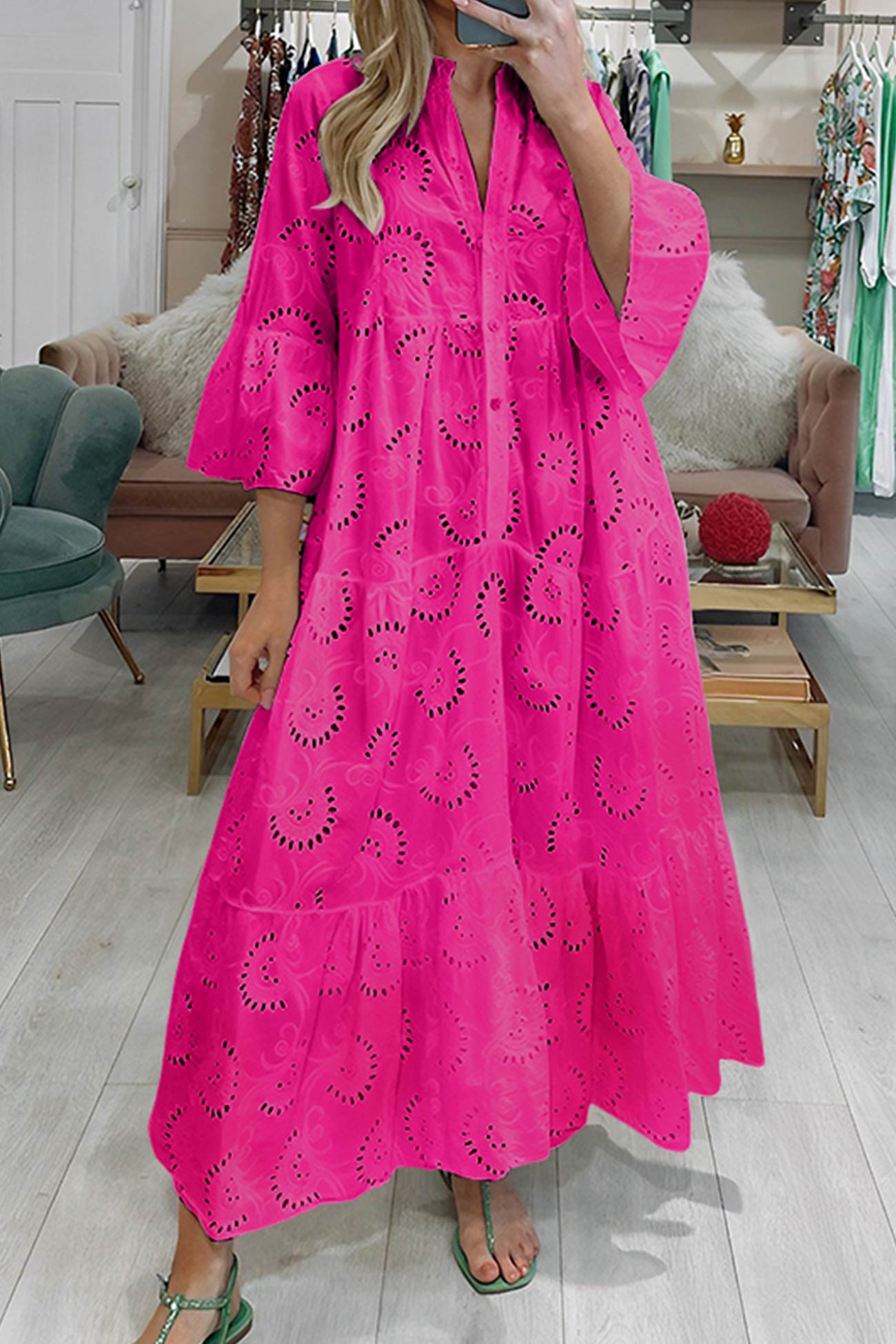 Woman wearing a bright pink dress with cut-out patterns in a store setting.