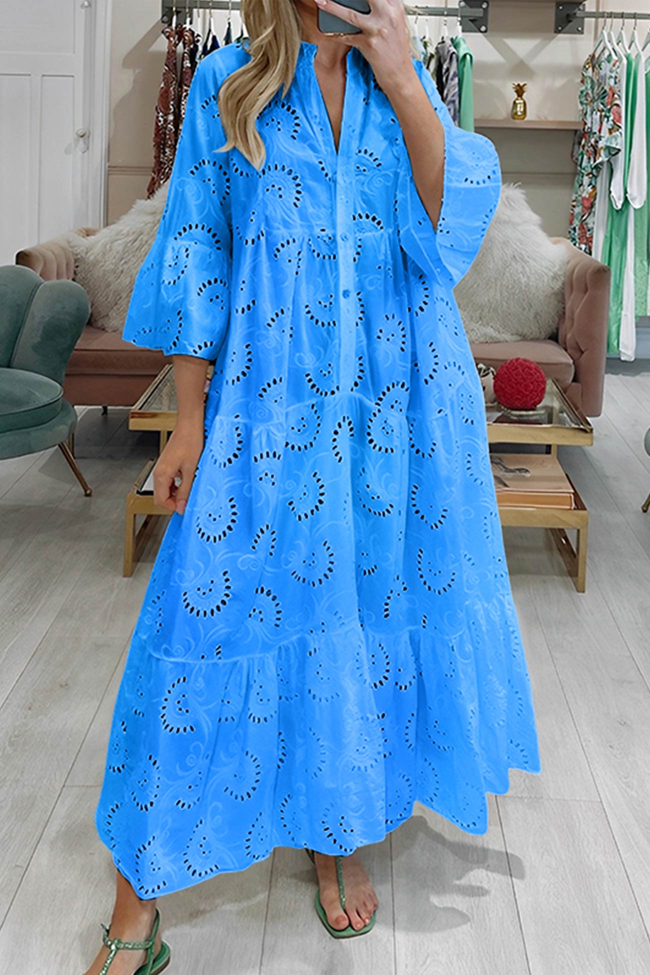 Woman wearing a blue dress with cut-out patterns in a store setting.