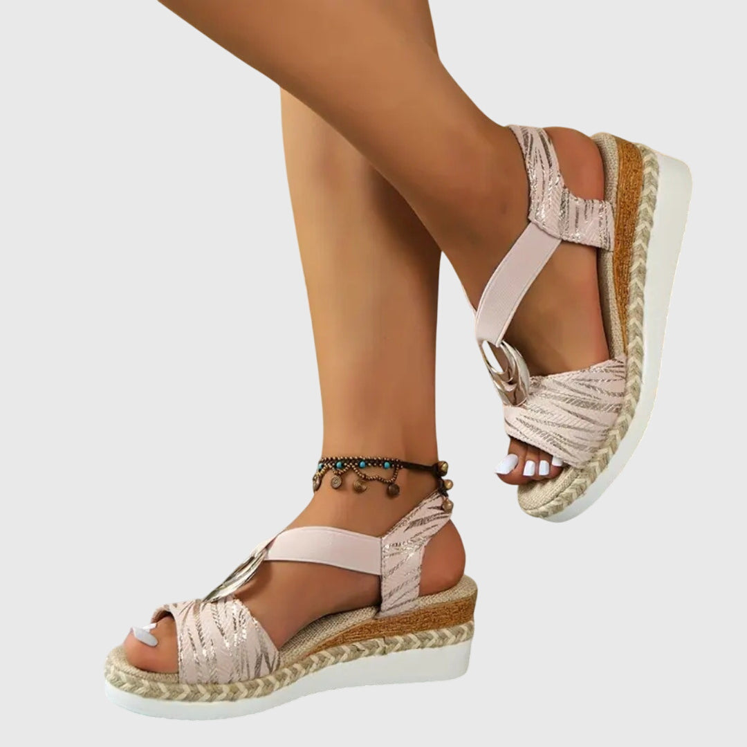 Beige sandals with cork sole worn by a person on a light gray background