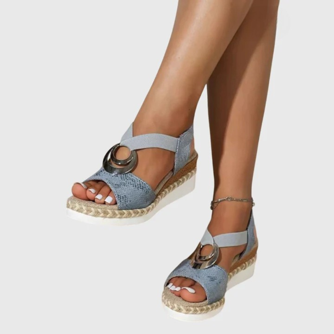 Blue sandals with cork sole worn by a person on a white background