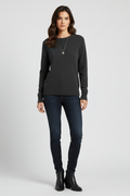Woman wearing a black sweater and jeans on a white background