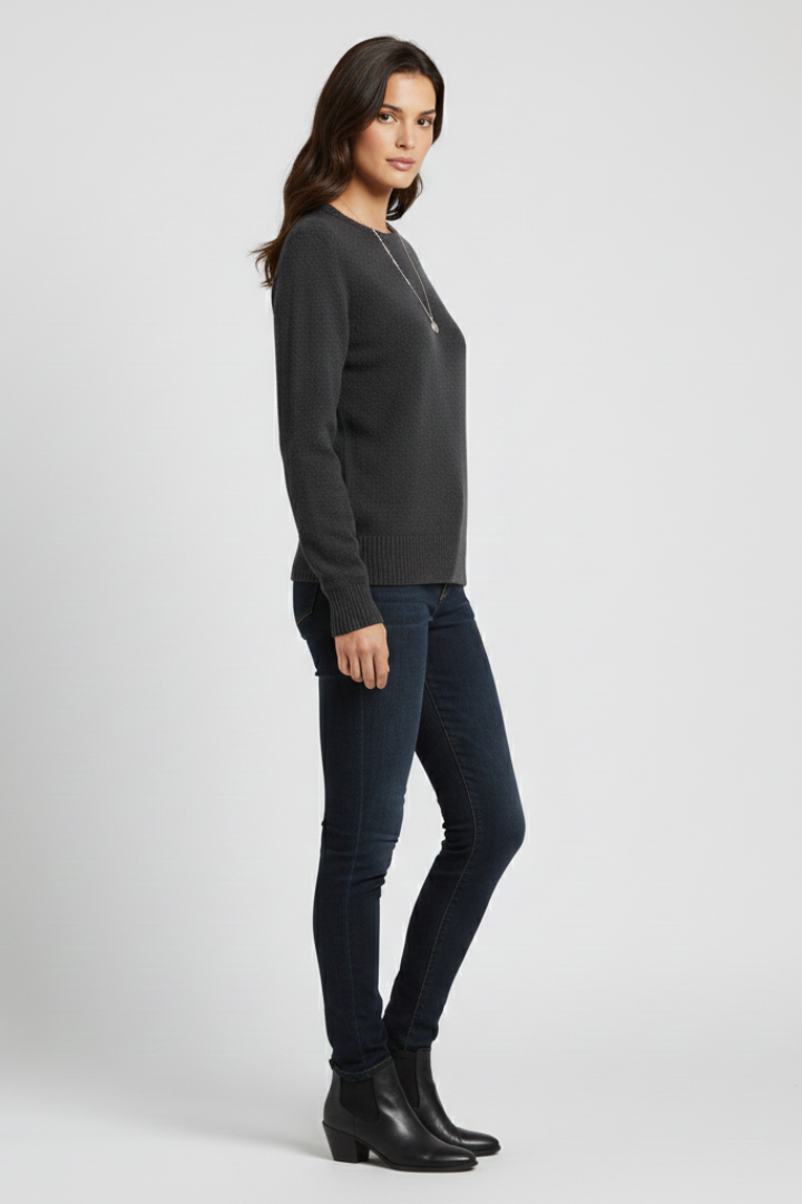 Woman wearing a dark gray sweater and black jeans on a white background