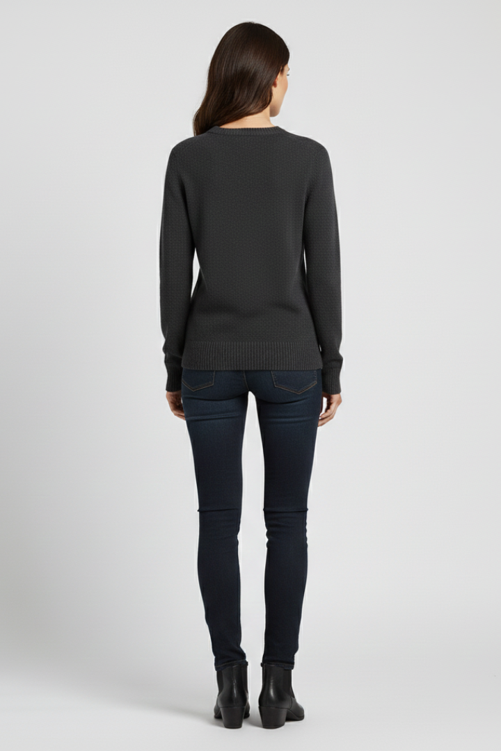 Person wearing a dark gray sweater and black pants on a light gray background