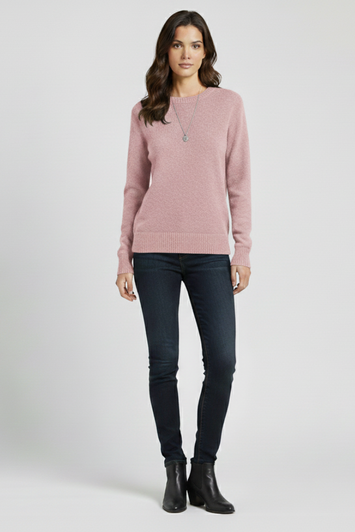 Woman wearing a pink sweater and dark jeans on a white background